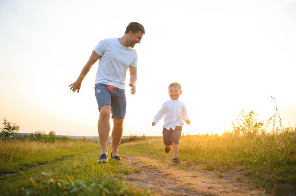 Happy father playing with son on sunset background .The concept of father's day. - Fotó, kép