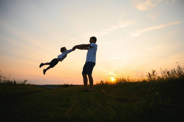 Father's day. Happy family father and toddler son playing and laughing on nature at sunset. - Photo, Image