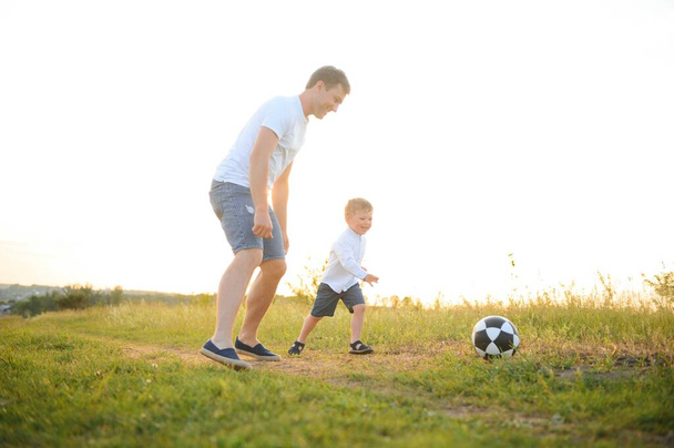 День отца. Отец и сын играют вместе на открытом воздухе летом. Счастливая семья, отец, сын на закате - Фото, изображение