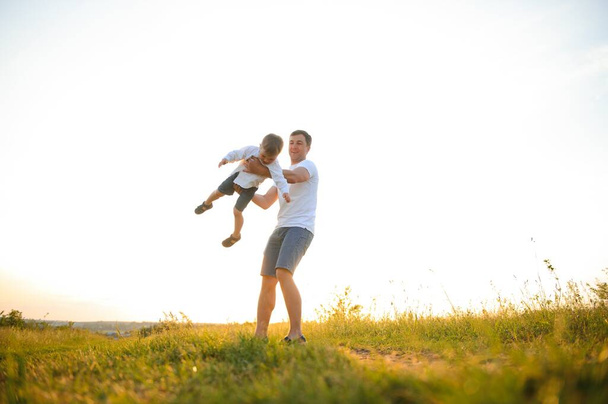 father's day. Dad and son playing together outdoors on a summer. Happy family, father, son at sunset - Photo, image
