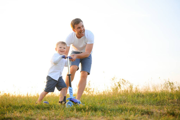 Vatertag. glücklicher Familienvater und Kleinkind-Sohn spielen und lachen bei Sonnenuntergang in der Natur. - Foto, Bild