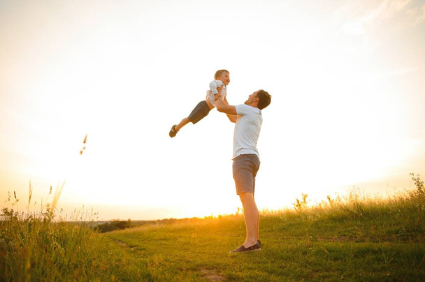 Apák napja. Apa és fia együtt játszanak a szabadban egy nyáron. Boldog család, apa, fiú naplementekor - Fotó, kép