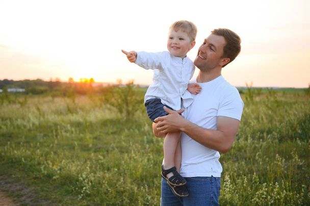 father's day. Dad and son playing together outdoors on a summer. Happy family, father, son at sunset - Fotó, kép