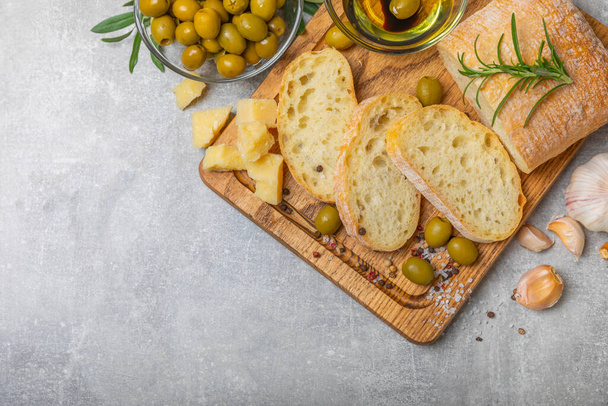 Ιταλικό ciabatta ψωμί κομμένο σε φέτες με μυρωδικά, ελιές, σάλτσα πέστο, σκόρδο και παρμεζάνα πάνω σε τσιμεντένιο τραπέζι. Φρέσκο σπιτικό ιταλικό ψωμί Ciabatta κομμένο σε φέτες με βότανα και μπαχαρικά.Τοποθετήστε το για κείμενο. copyspace. - Φωτογραφία, εικόνα