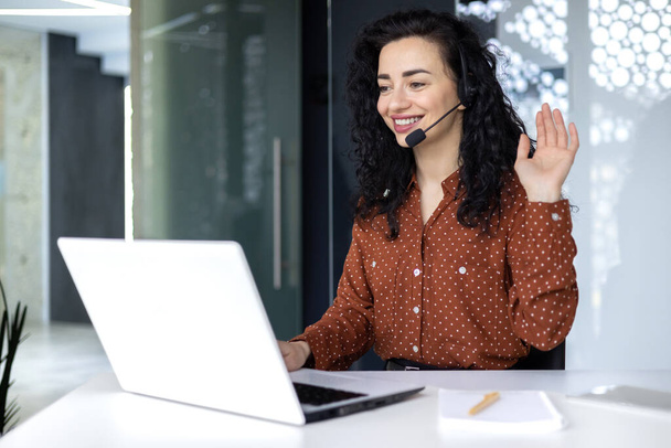 Video call online meeting with colleagues, Hispanic woman working inside modern office, businesswoman smiling and talking remotely using laptop and headset. - Fotoğraf, Görsel
