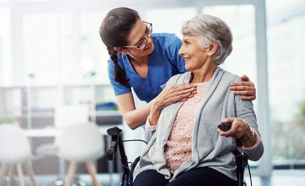 Я хочу, чтобы ваше пребывание здесь было максимально приятным. молодая медсестра разговаривает со своим пожилым пациентом в доме престарелых - Фото, изображение