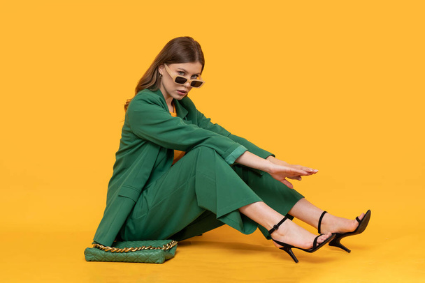 Modna modelka w duym для жінок Модна жіноча модель в ослабленому зеленому костюмі на ізольованому жовтому тлі
. - Фото, зображення
