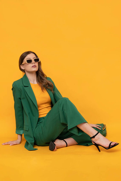 Modna modelka w duym zielonym Fashionable female model in oversized green suit on isolated yellow background. - Photo, Image