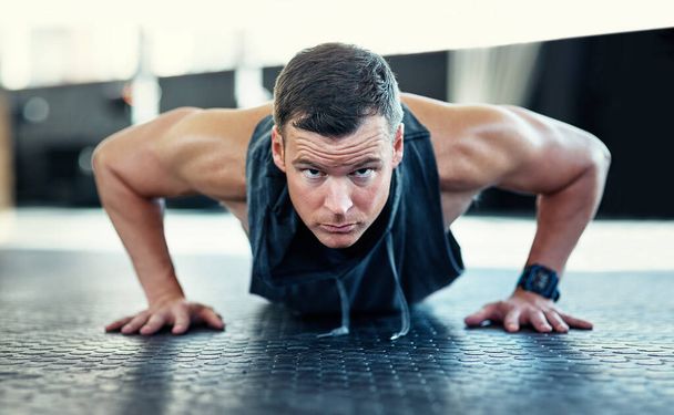 Do your push ups and dont give up. a young man doing push ups in a gym - 写真・画像