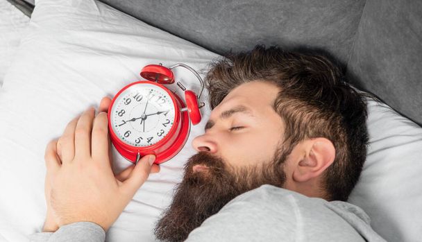 Portrait of man sleeping with alarm clock in bed, sleep time. - Фото, изображение
