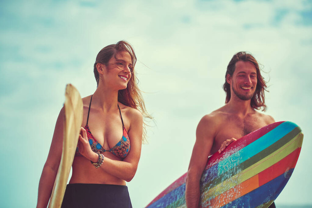 El surf nos acerca más. una joven pareja caminando por la playa con sus tablas de surf - Foto, Imagen