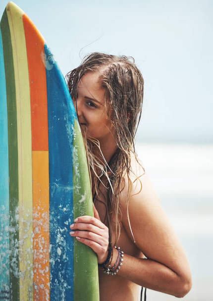 Tijd om wat golven te vangen. een aantrekkelijke jonge vrouw staat op een strand met een surfplank - Foto, afbeelding