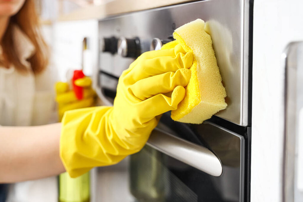 Домохозяйка чистит электрическую духовку с губкой на кухне, крупным планом - Фото, изображение