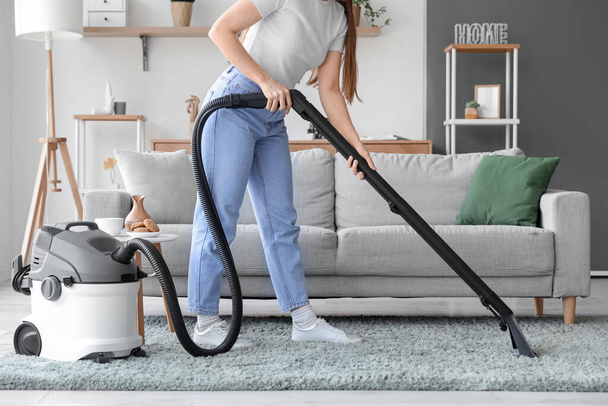 Junge Frau saugt Teppich zu Hause - Foto, Bild