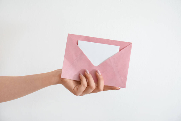 Woman holding envelope with blank invitation card on white background - Foto, afbeelding