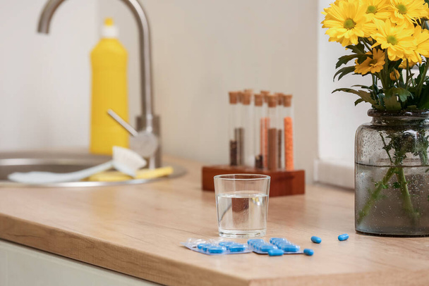 Folic Acid pills and glass of water on counter in kitchen, closeup - Zdjęcie, obraz