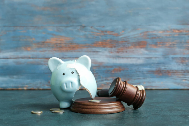 Broken patched piggy bank with judge gavel and money on grunge background. Bankruptcy concept - 写真・画像
