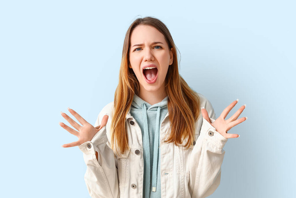 Angry young woman shouting on blue background - Zdjęcie, obraz