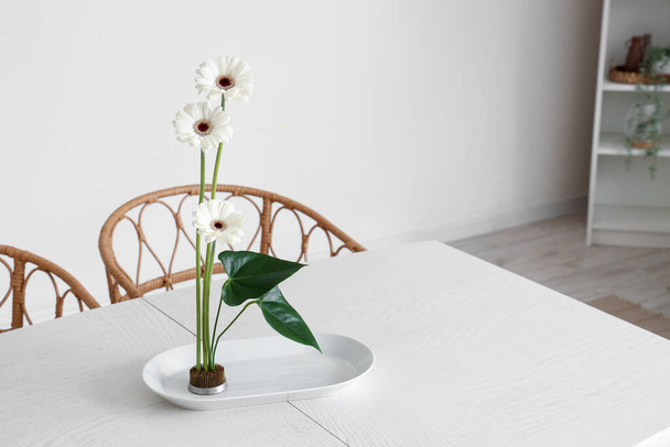 Beautiful ikebana on dining table in room - Foto, afbeelding