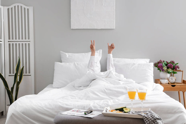 Morning of young woman showing victory gesture and thumb-up in bed - Photo, Image