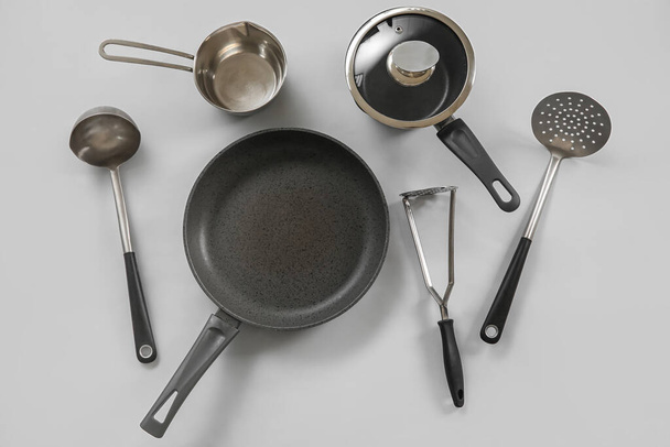 Cooking pot, frying pan and kitchen utensils on grey background - Fotó, kép