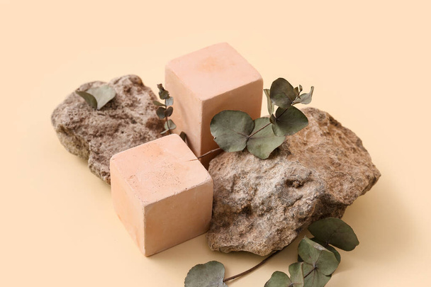 Decoratieve stenen podia met eucalyptus op beige achtergrond - Foto, afbeelding