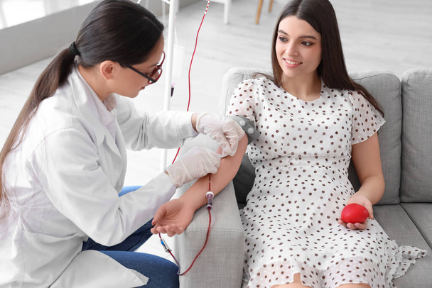 Médecin féminin prenant du sang de jeune donneur en clinique - Photo, image