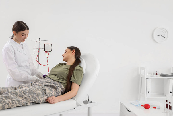 Médecin prenant le sang d'une femme soldat à la clinique - Photo, image