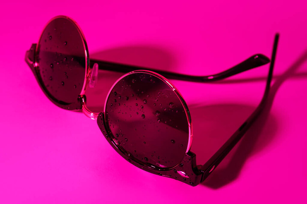 Stylish sunglasses with water drops on pink background - Photo, Image