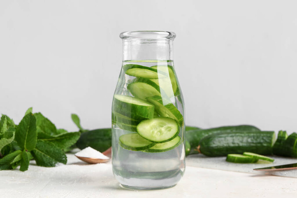 Bottle of infused water with cucumber slices on white table - Foto, Imagem