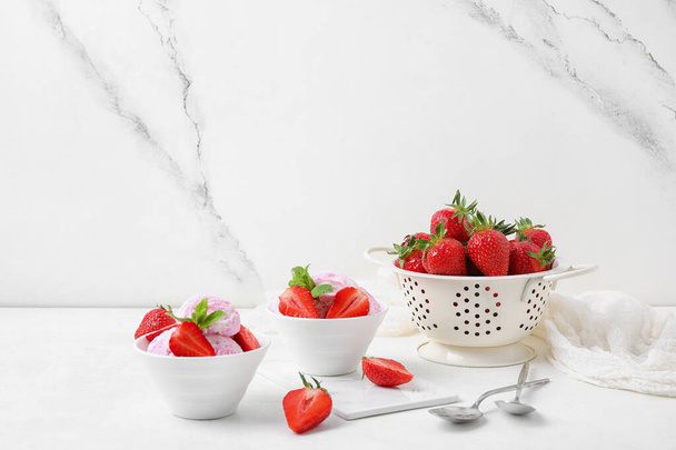 Cuencos de helado de fresa con bayas y menta en la mesa blanca cerca de la pared grunge - Foto, imagen