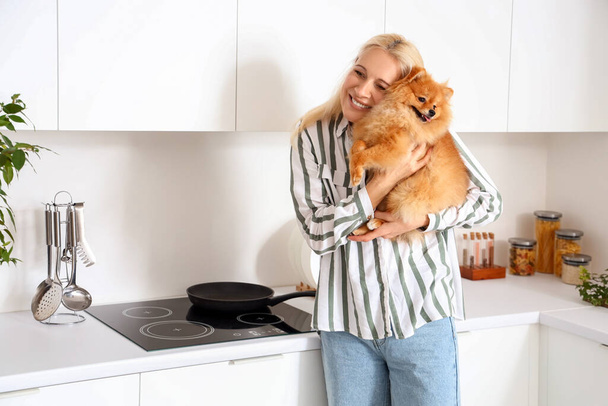 Mujer madura con perro Pomerania en la cocina - Foto, Imagen