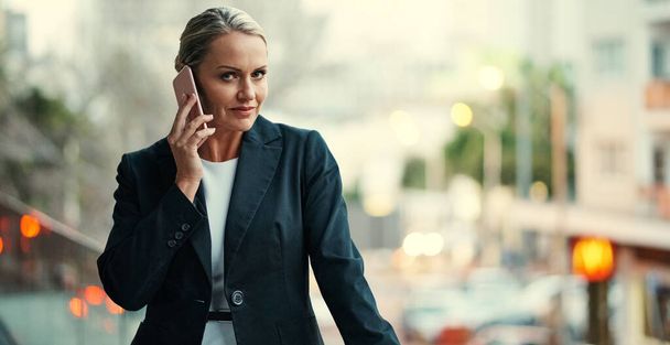 Communication is a key part of success. Cropped portrait of an attractive mature businesswoman using her cellphone while standing on the balcony of her office - Foto, Imagen