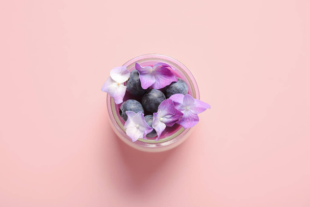 Ποτήρι πανακότα με μύρτιλλα και όμορφα λουλούδια ορτανσία σε ροζ φόντο - Φωτογραφία, εικόνα