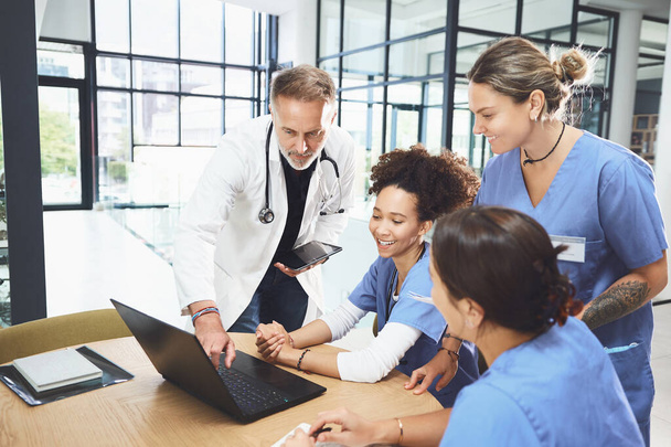Ez az információ segíthet a diagnózisunkban. egy csapat orvos, akik laptopot használnak egy kórházban tartott megbeszélés során. - Fotó, kép