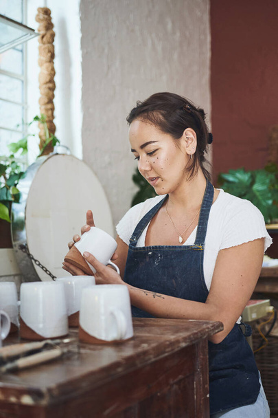 As perfect as every piece should be. a young woman making mugs in a pottery studio - Foto, Imagem