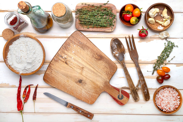 tabla de cortar, ingredientes y especias en una mesa de cocina blanca. Vista desde arriba. Espacio para texto y menú. - Foto, imagen