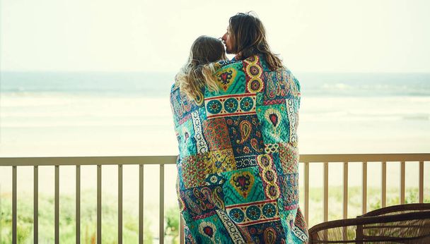 Si proches qu'ils ne font qu'un. un jeune couple affectueux enveloppé dans une couverture sur le balcon - Photo, image