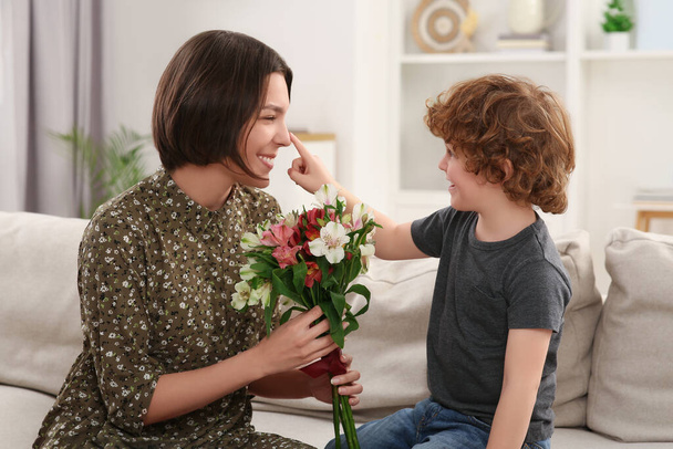 Little son congratulating his mom with Mother`s day at home. Woman holding bouquet of flowers - Valokuva, kuva