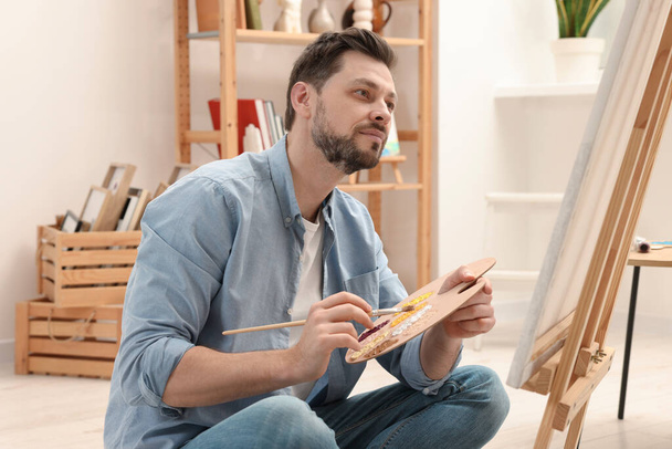 Handsome man painting in studio. Creative hobby - Valokuva, kuva