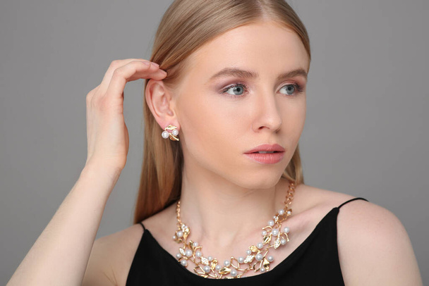 Beautiful young woman with elegant jewelry on gray background - Foto, Imagem
