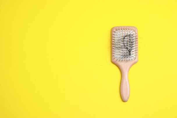 Wooden brush with lost hair on yellow background, top view. Space for text - Fotoğraf, Görsel