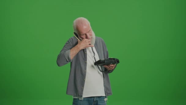 Yeşil Ekran. Gri sakallı yaşlı bir adam antika bir telefonla konuşuyor. Eski telefonları topluyor ve koruyor.. - Video, Çekim