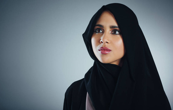 Pek çok şeyi sorgular ama inancını sorgulamaz. Genç Müslüman bir iş kadınının gri bir arka planda çekilmiş bir fotoğrafı. - Fotoğraf, Görsel