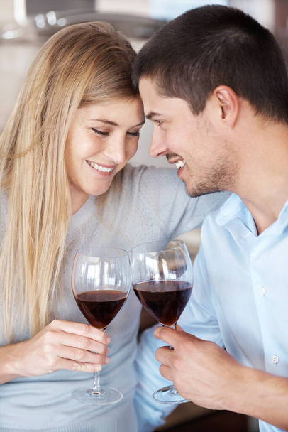 Spending some down time together. A couple in love enjoying a glass of red wine - Foto, afbeelding