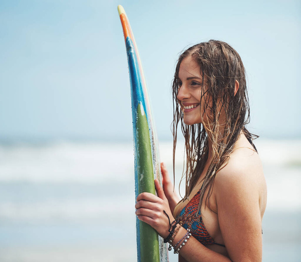 Ela vive para surfar. uma jovem mulher atraente de pé em uma praia com uma prancha de surf - Foto, Imagem