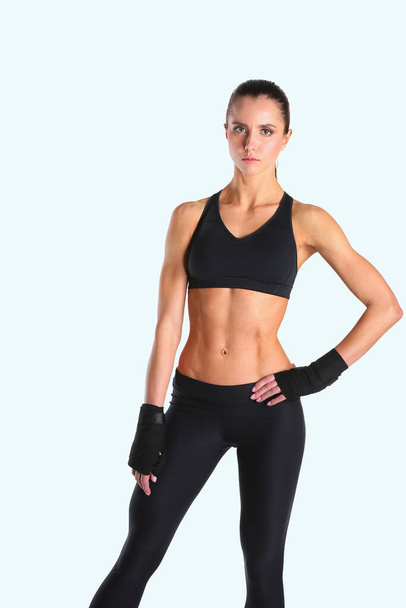 Muscular young woman posing in sportswear against black background - Foto, Imagen