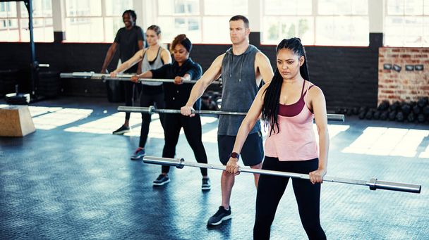 Mostrando dedicação, disciplina e respeito próprio. um grupo de fitness usando barras de aço em sua sessão no ginásio - Foto, Imagem