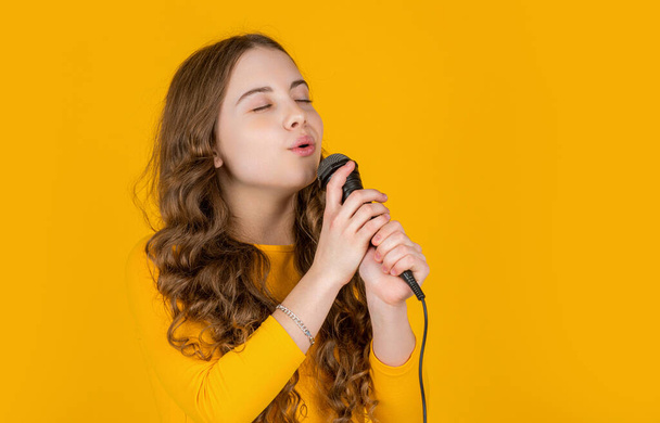 musical teen girl with microphone on yellow background. - Fotoğraf, Görsel
