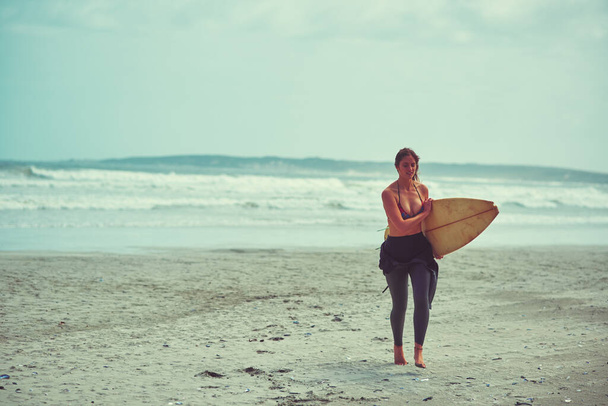 That was a wavy ride. a young surfer carrying her surfboard on the beach - Photo, Image